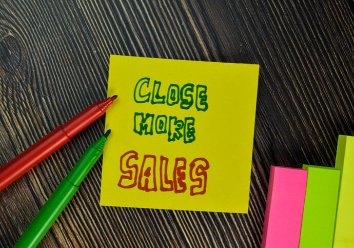 Close More Sales write on sticky note isolated on Wooden Table. Business concept