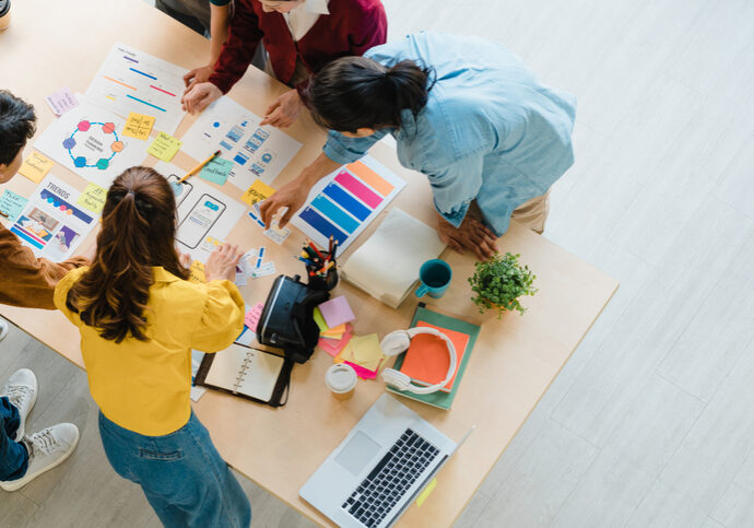 Multiracial group of young creative people in smart casual wear discussing business brainstorming meeting ideas mobile application software design project in modern office. Coworker teamwork concept.