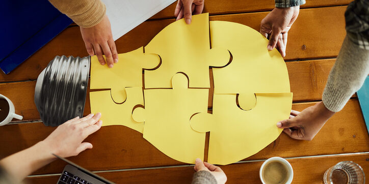 Above view of unrecognizable creative team cooperation while making light bubble of puzzles at casual office.